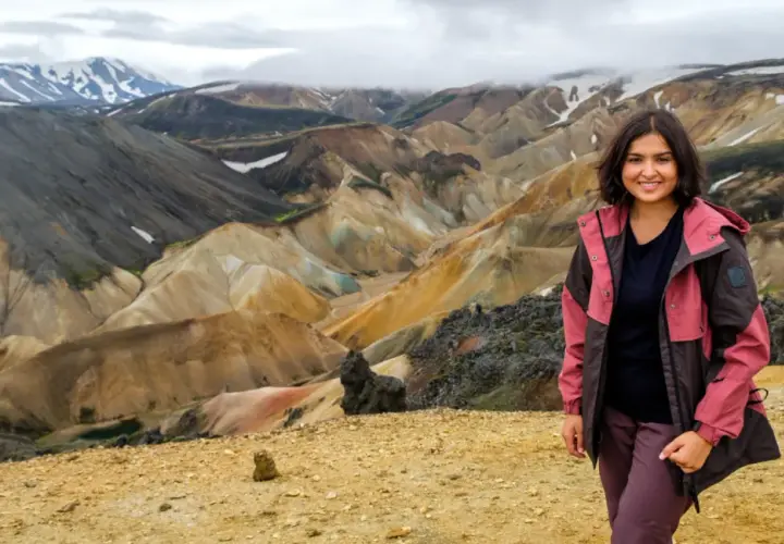 Uśmiechnięta kobieta na tle barwnych gór Landmannalaugar na Islandii.