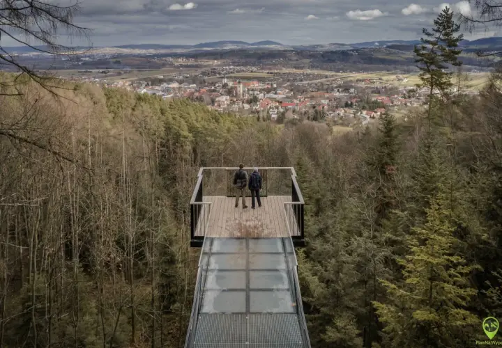Dwie osoby stoją na szklanym tarasie widokowym, podziwiając panoramę Starego Sącza. To jedna z głównych atrakcji turystycznych regionu.