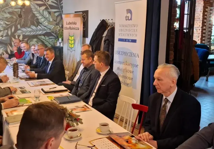 Ludzie siedzący przy stole podczas spotkania, na ścianie banery "Lubelska Izba Rolnicza" i "TUW Ubezpieczenia".