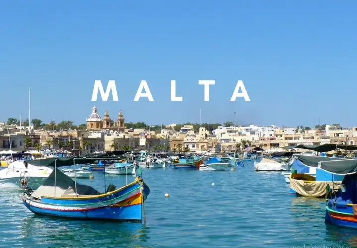 Malta we wrześniu: kolorowe łodzie luzzu kołyszą się na lazurowej wodzie, w tle malownicze miasteczko. Idealna pogoda na podróż.