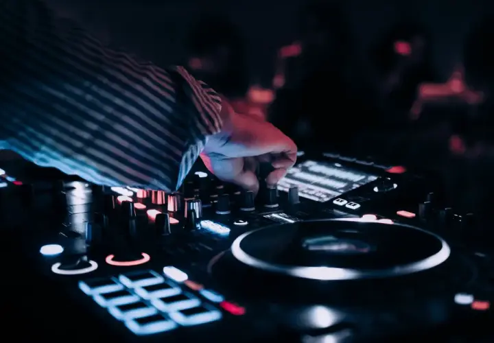 Dłoń DJ-a kręci gałką miksera, tworząc muzykę na wesele. Zastanawiasz się, ile kosztuje dj na wesele?