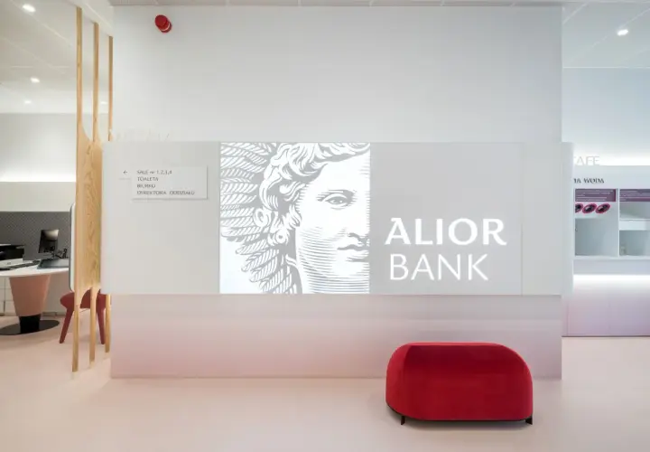 Nowoczesne wnętrze oddziału Alior Bank z logo banku, grafiką i czerwonym pufem.