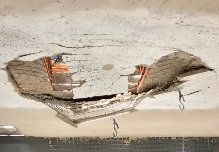 Soffitto sfondato che rivela la struttura del solaio sottostante, con mattoni e armatura a vista.