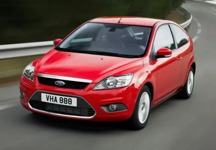 Czerwony Ford Focus MK2 1.6 benzyna w ruchu na zakręcie drogi.