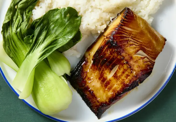 A glistening piece of black cod, marinated and seared to perfection, sits beside fluffy white rice and vibrant green bok choy.