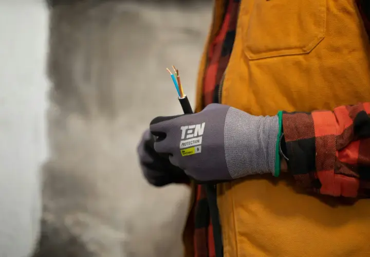 Elektryk w rękawicach ochronnych trzyma kabel elektryczny.