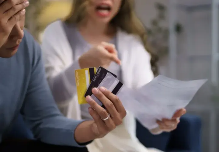 Kłótnia o finanse. Czy mąż powinien dawać żonie pieniądze? Para z kartami kredytowymi i rachunkami w rękach.