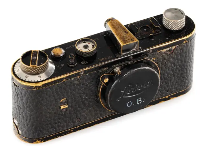 Czarny, zabytkowy aparat Leica z widocznymi śladami użytkowania, jeden z najdroższych starych aparatów fotograficznych, z wygrawerowanym napisem "OSCAR BARNACH".