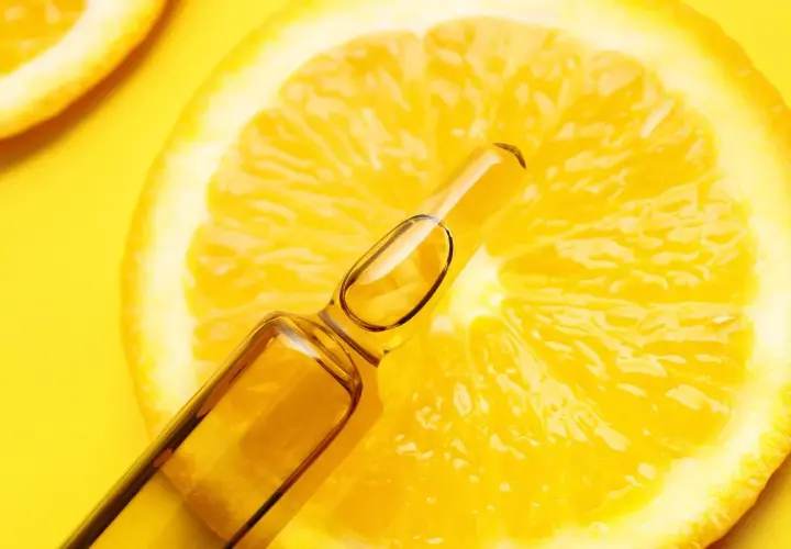 Fetta di limone brillante con fiala di siero alla vitamina C, un concentrato di freschezza e benessere.