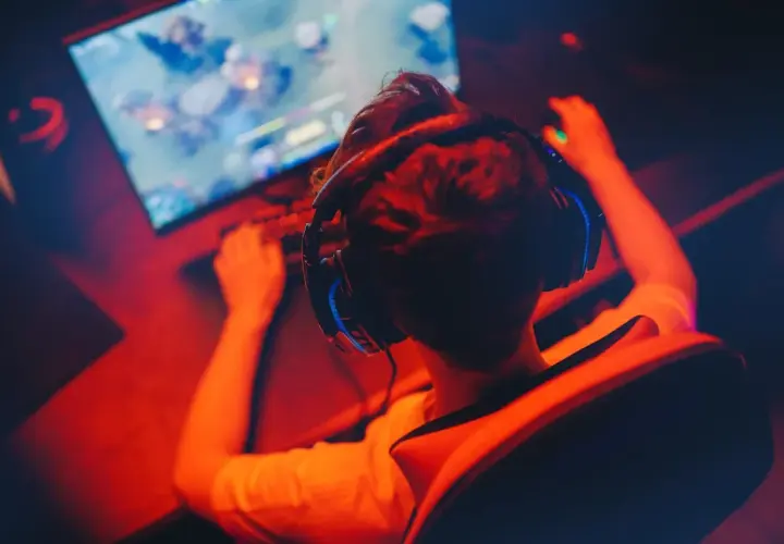 Gracz w słuchawkach przed monitorem, przygotowuje się do gry. Chcesz wiedzieć, jak zarejestrować się na Steamie?
