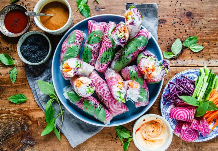 Vackra vietnamesiska vårrullar med kyckling, färska grönsaker och en krämig dippsås. Serveras med en sidoplatta av grönsaker och rödbetor.