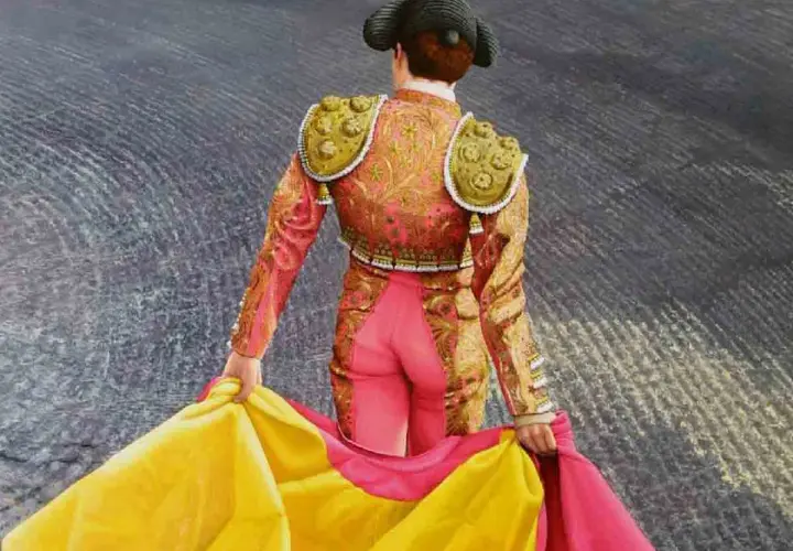Torero con traje de luces rosa y dorado, sujetando un capote amarillo y rosa. Aprende como hacer un capote de torero.
