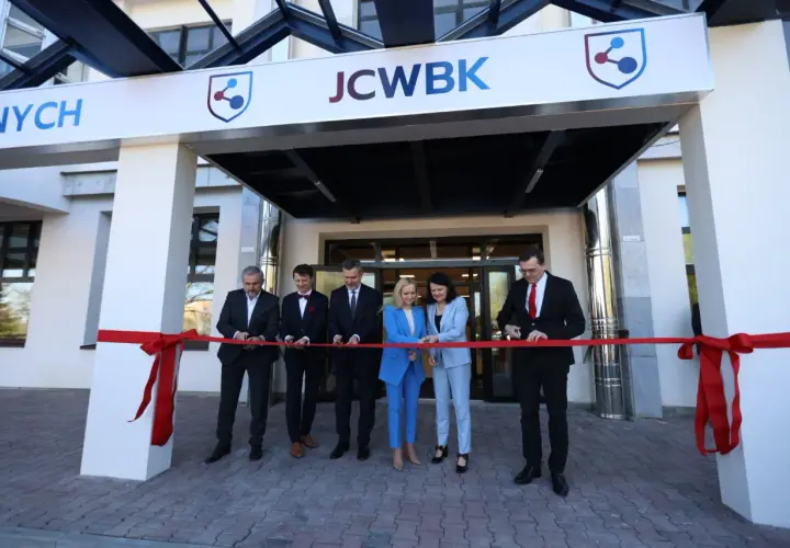 Otwarcie placówki: ludzie przecinają czerwoną wstęgę przed budynkiem z logo JCWBK.