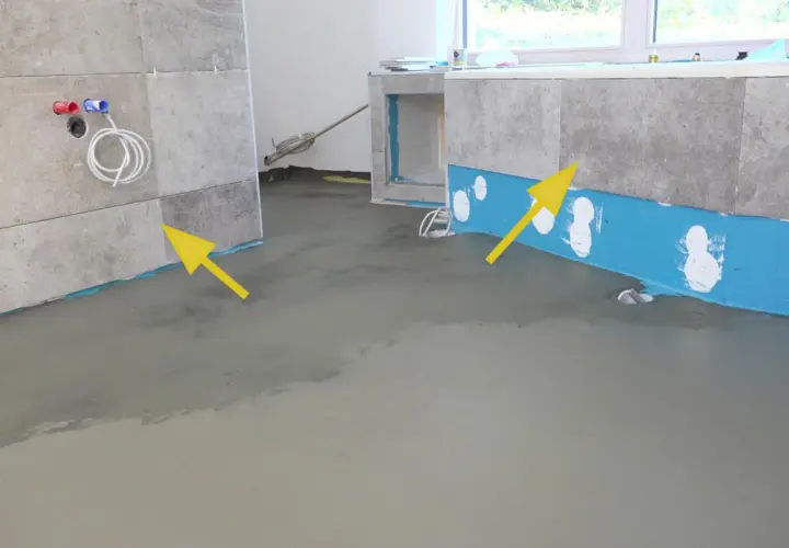 Badezimmer abdichten: blaue Dichtungsbahn und frischer Estrich zeigen den Fortschritt. Gelbe Pfeile markieren wichtige Bereiche.