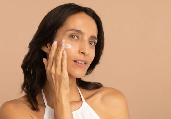 Une femme applique une crème hydratante pour lutter contre la peau sèche.