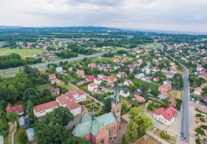 Widok z lotu ptaka na Wola Rzędzińska: kościół, domy, droga i tereny zielone.