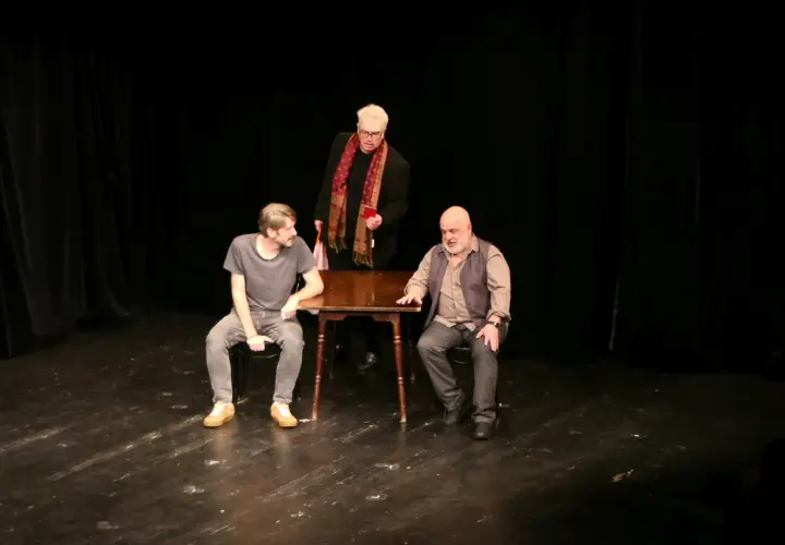 Trzej mężczyźni na scenie Teatru Korez, Plac Sejmu Śląskiego Katowice. Jeden stoi, dwóch siedzi przy stole.