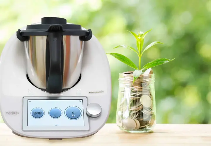 Thermomix i słoik z monetami, symbolizujące oszczędność energii. Dowiedz się, ile prądu pobiera Thermomix, by gotować ekonomicznie.