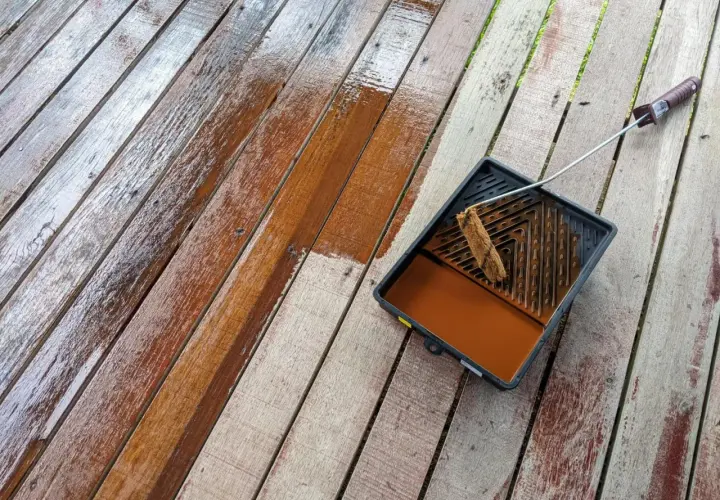 Malowanie boazerii na tarasie. Drewno odzyskuje blask dzięki brązowej lazurze.