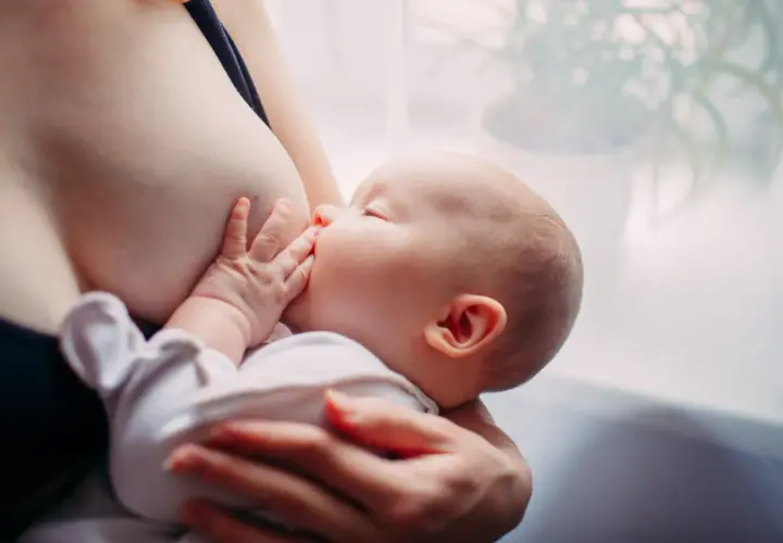 Un neonato si nutre al seno. Scopri come aumentare il latte materno in modo naturale per il benessere del tuo bambino.