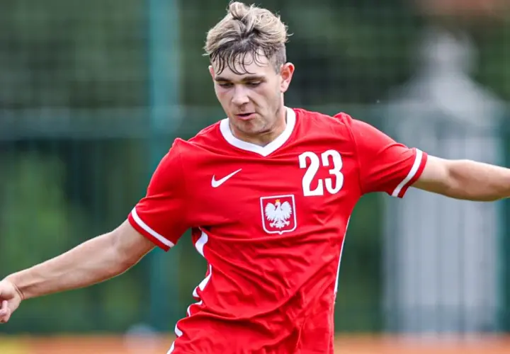 Piłkarz Rakowa w czerwonej koszulce z numerem 23 i godłem Polski, gotowy do gry w Lidze Europy.