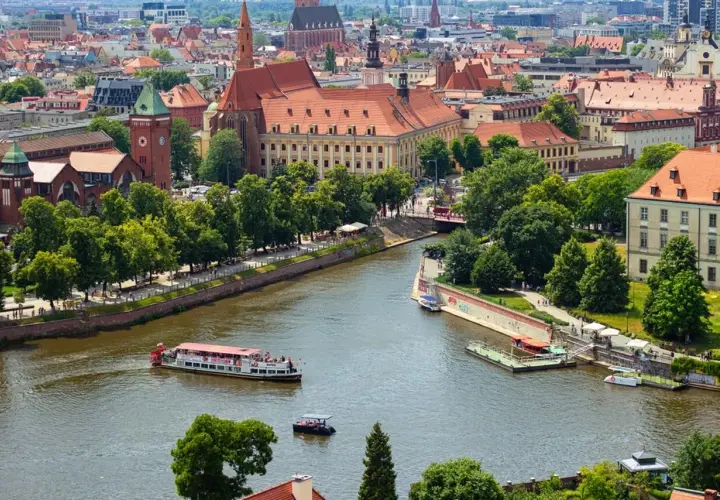 Wrocław inwestycje: malowniczy widok na Odrę z zabytkową architekturą i statkami wycieczkowymi.