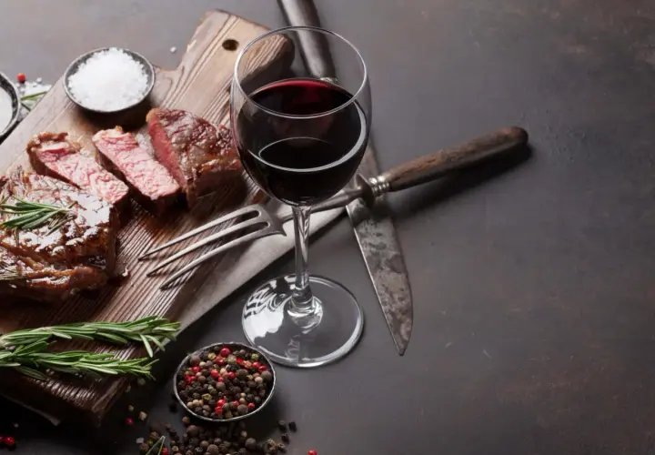 Un verre de vin malbec, parfait pour accompagner ce steak juteux. Une dégustation qui évoque la richesse d'une belle région viticole.