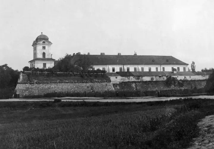 Zamek w Rzeszowie z wieżą i długim budynkiem, otoczony kamiennym murem.