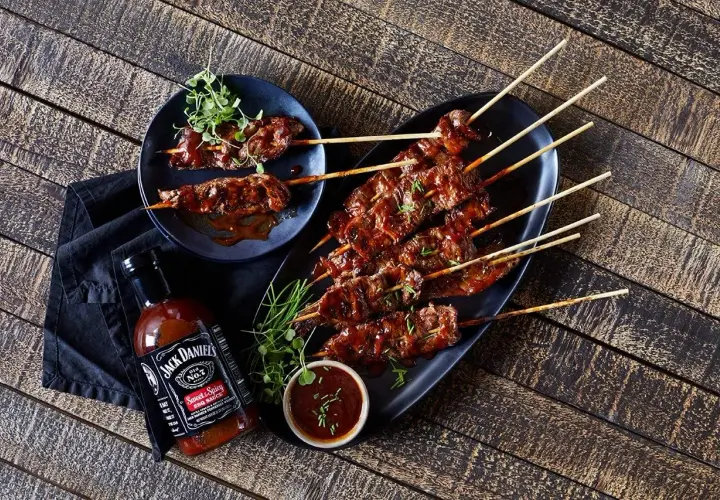 Brochettes de bœuf glacées à la marinade Jack Daniel's, servies avec une sauce barbecue.