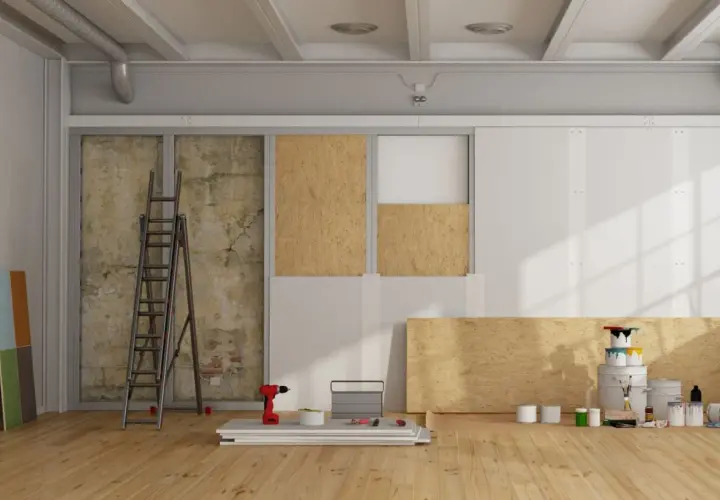 Chantier de rénovation avec panneaux de bois, échelle, outils et pots de peinture.