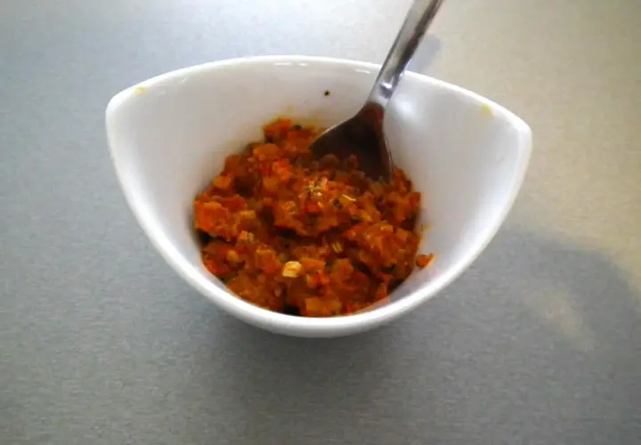 Czerwona pasta curry w białej miseczce z łyżką.