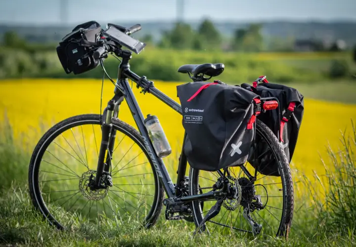 Rower z sakwami Extrawheel gotowy na wyprawę. Jakie sakwy rowerowe wybrać na długą trasę? Te czarne, wodoodporne, z czerwonymi akcentami, wyglądają na solidne.