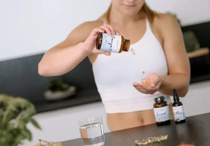 Frau nimmt Omega-3-Kapseln ein, um ihr Wohlbefinden zu fördern.