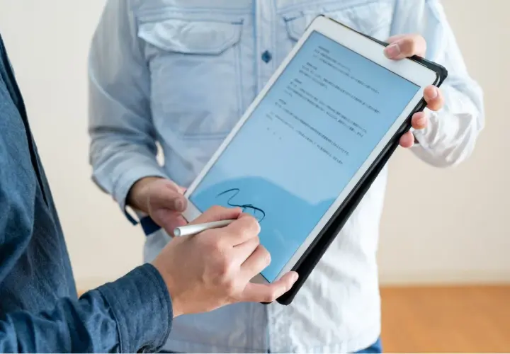 Firma electrónica en tablet, un hombre firma un documento digital con un stylus. El acto tiene pleno p.p. significado jurídico.