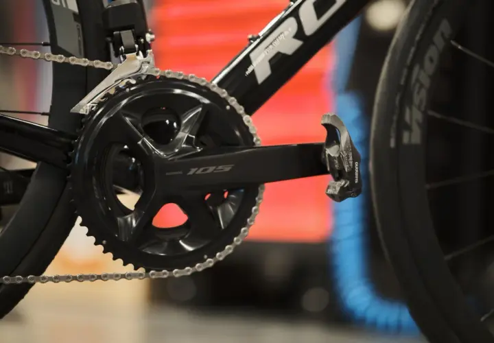 Czarna korba Shimano 105 z rowerowym łańcuchem i pedałem. Gotowa do jazdy po szosie.
