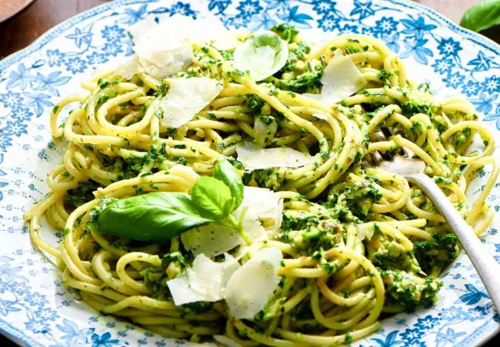 Pâtes au pesto, une recette italienne savoureuse avec des copeaux de parmesan et des feuilles de basilic frais.