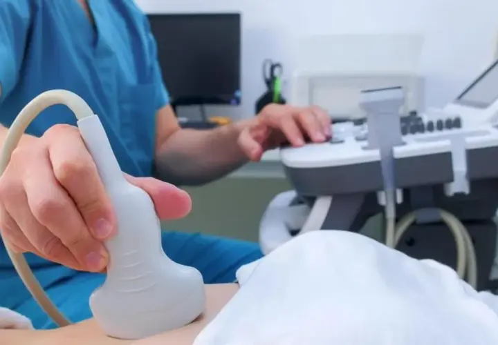 Lekarz wykonuje badanie USG, aby zbadać trzustkę pacjenta. Aparatura i sonda są widoczne.