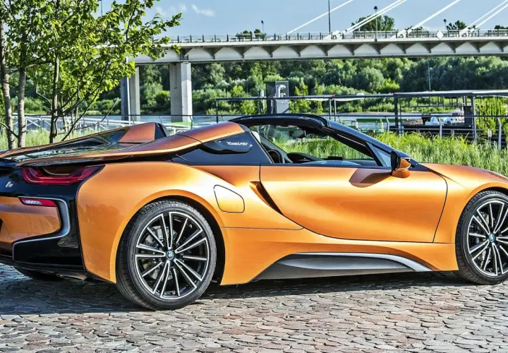 Pomarańczowy BMW i8 Roadster na bruku, pod mostem. Sprawdź aktualną bmw i8 cena.