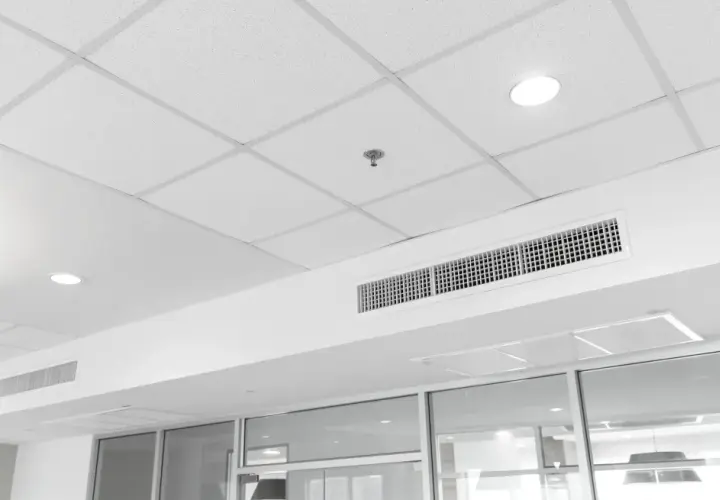 Soffitto modulare bianco con faretti, bocchette di ventilazione e un sistema di controsoffitto autoportante che nasconde gli impianti.