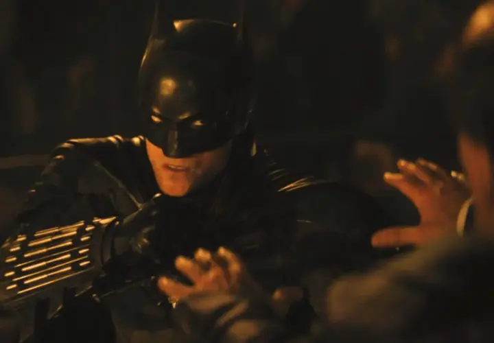 Batman i mörk dräkt, redo för strid i en av filmerna med Batman. En hand syns i förgrunden.
