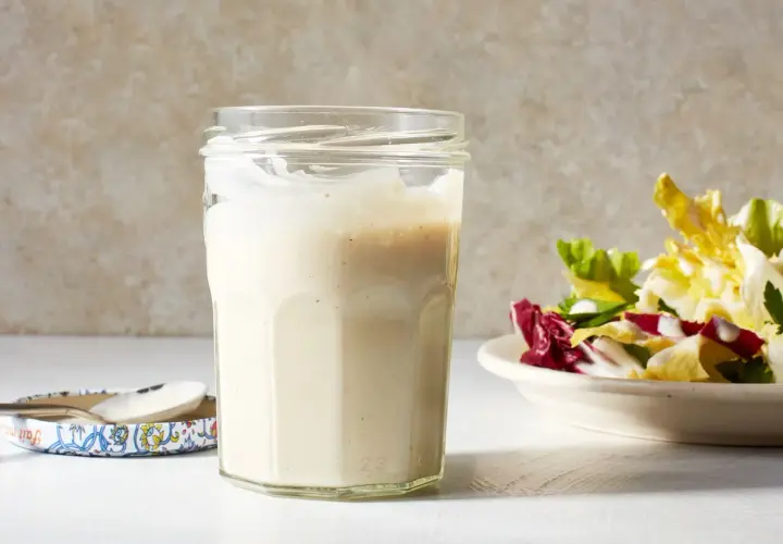 A jar of creamy miso dressing sits next to a fresh salad, ready to add a savory umami kick.