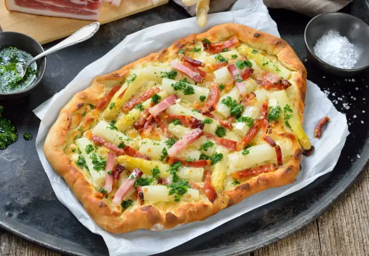 Pyszna pizza ze szparagami i boczkiem, posypana świeżą natką pietruszki. Idealna na wiosenny obiad.