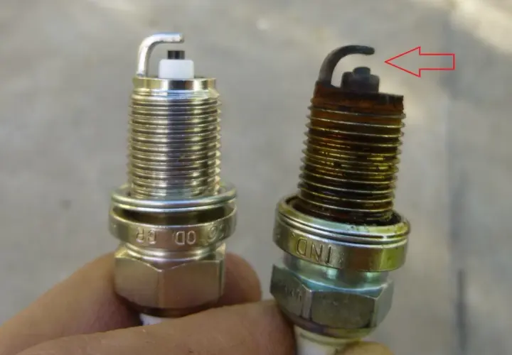 Una bujía nueva y otra desgastada, con óxido y el electrodo doblado. Así puedes saber si las bujías están mal.