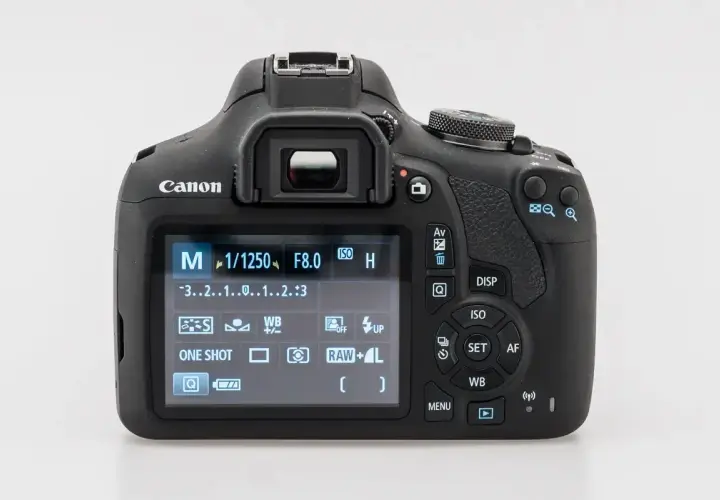 Tył aparatu Canon z widocznym ekranem LCD pokazującym ustawienia manualne (M), czas 1/1250s, przysłonę F8.0, ISO i inne parametry. Dowiedz się, jak dobrze ustawić aparat Canon.