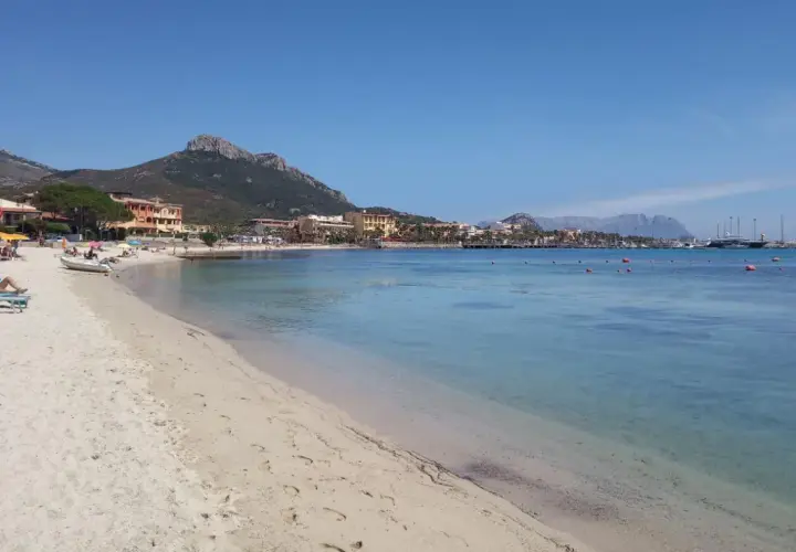 Plage de sable fin, eaux turquoise et montagnes en arrière-plan. Un rêve d'aranci in Sardegna.