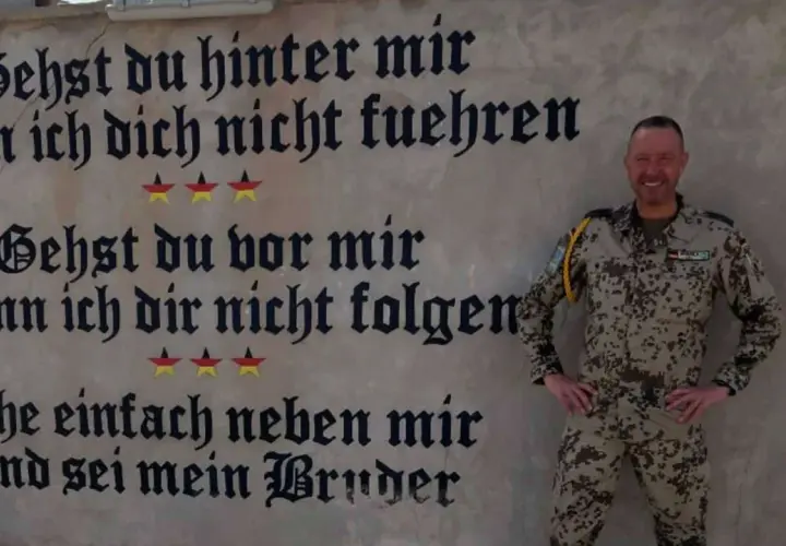 Ein Soldat der Bundeswehr steht vor einer Wand mit inspirierenden Bundeswehr Zitaten. "Gehe einfach neben mir und sei mein Bruder.