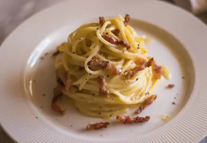 Pyszna, prawdziwa carbonara na talerzu, z chrupiącym guanciale i kremowym sosem. Idealna na włoski obiad.