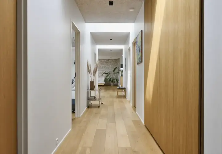 Un luminoso vano di disimpegno con pavimenti in legno chiaro, pareti bianche e armadi in legno.