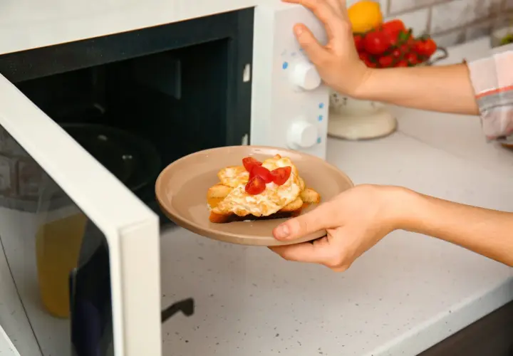 Piatto con toast, uova e pomodorini appena sfornati dal microonde.