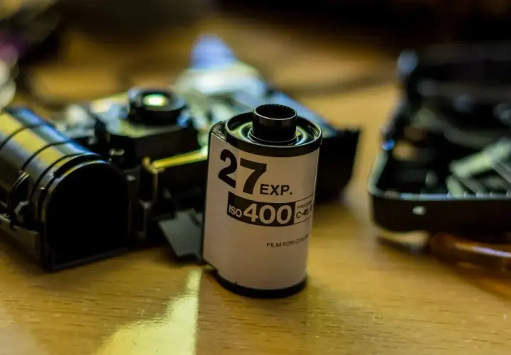 Rolka filmu 35mm ISO 400, obok rozebranego aparatu, czeka na budowę obiektywu.